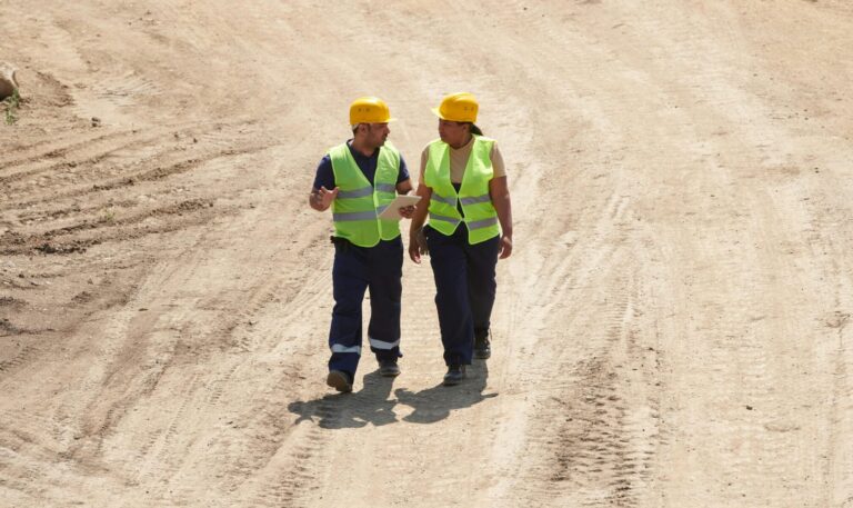 Two workers walking together on barren land